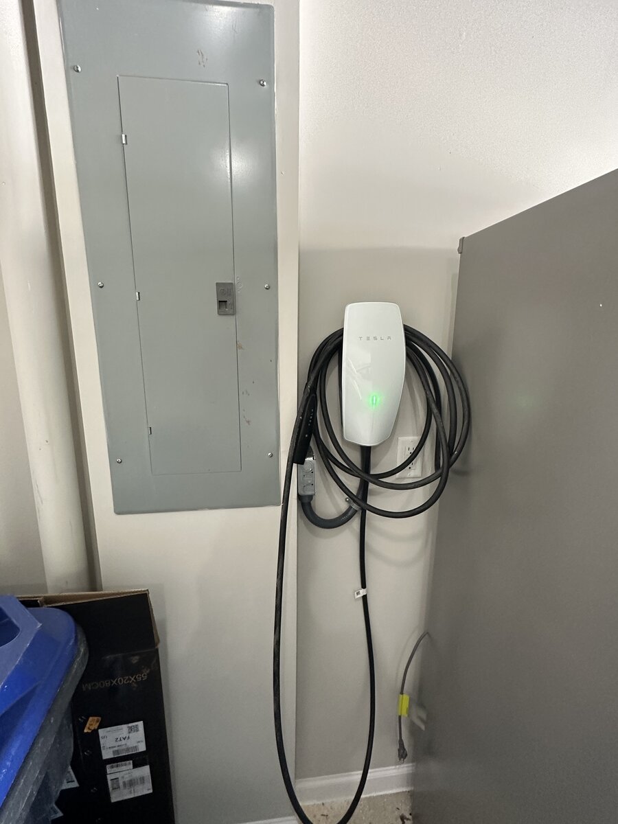 Tesla EV charger installed on exterior brick wall